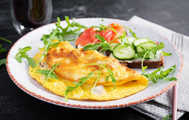 Café da manhã. Omelete com queijo e sanduíches com salmão e pepino na chapa branca. Frittata - omelete italiana.