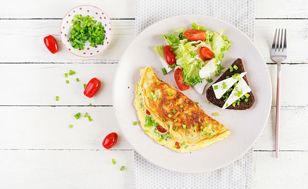 Café da manhã. Omelete com tomate, queijo, cebolinha e sanduíche com queijo feta. Frittata - omelete italiana. Vista superior, acima