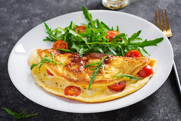 Café da manhã. Omelete com tomate, queijo e salada na chapa branca. Frittata - omelete italiana.