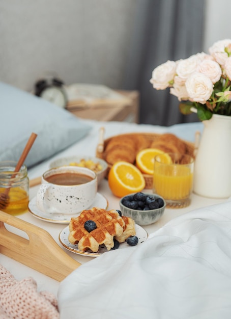 Café da manhã romântico com suco de laranja de waffles de café e flores rosas