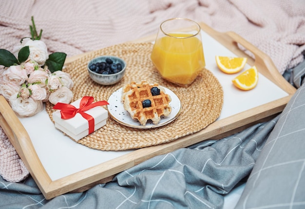 Café da manhã romântico com suco de laranja de waffles e flores rosas e caixa de presente