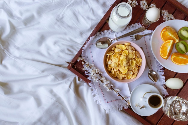 Foto café da manhã romântico na cama com flores da primavera. configuração plana, cópia espaço