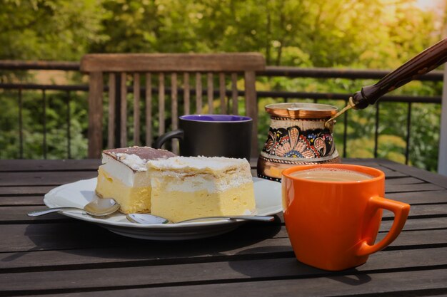 Café da manhã rústico. mesa de centro de madeira com xícaras de café, cezve, bolo de creme lake bled, deliciosa sobremesa eslovena. kremna rezina ou cremeschnitte