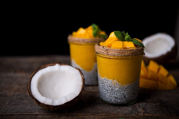 Café da manhã saudável caseiro, pudim de chia com leite de coco e manga em uma mesa de madeira, copie o espaço