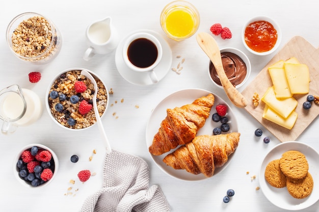 Café da manhã saudável com granola, amora, nozes, croissant, geléia, chocolate e café. Vista do topo