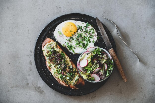 Café da manhã saudável com ovo frito de torrada de abacate e salada verde