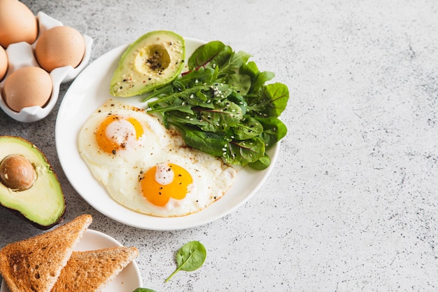 Café da manhã saudável com ovos de torradas de pão integral com salada verde abacate tradicional café da manhã