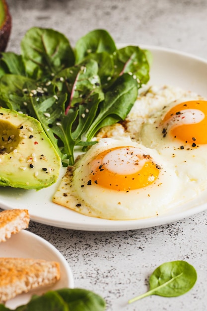 Café da manhã saudável com ovos de torradas de pão integral com salada verde abacate tradicional café da manhã