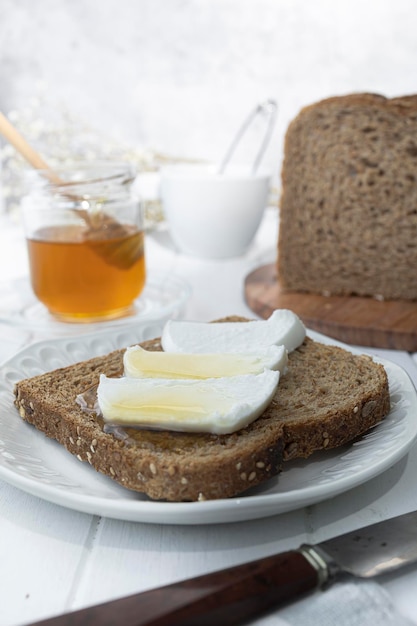 Café da manhã saudável com queijo de cabra fresco de pão integral e mel cru Um delicioso café da manhã