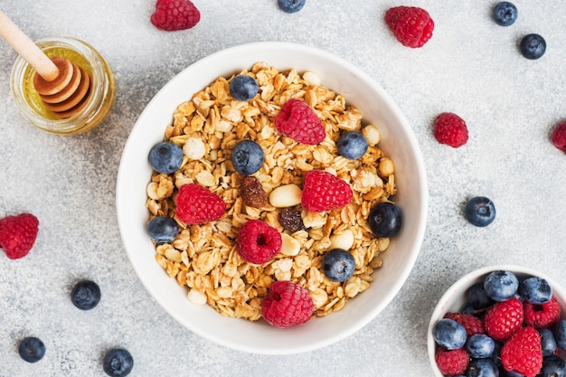 Café da manhã saudável. Granola fresca, muesli com iogurte e frutas na mesa cinza. Copie o espaço