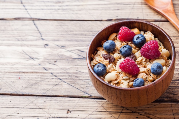 Café da manhã saudável. Granola fresca, muesli com iogurte e frutas na superfície de madeira