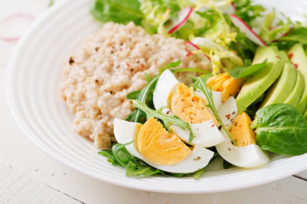 Café da manhã saudável. Menu dietético. Mingau de aveia e salada de abacate e ovos.