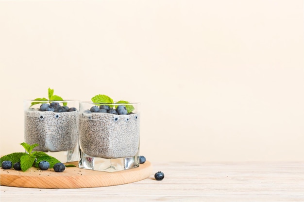 Café da manhã saudável ou manhã com sementes de chia pudim de baunilha e bagas de mirtilo no fundo da mesa dieta alimentar vegetariana e conceito de saúde Pudim de chia com leite de coco e mirtilo