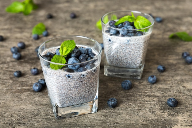 Café da manhã saudável ou manhã com sementes de chia pudim de baunilha e bagas de mirtilo no fundo da mesa dieta alimentar vegetariana e conceito de saúde pudim de chia com leite de coco e mirtilo