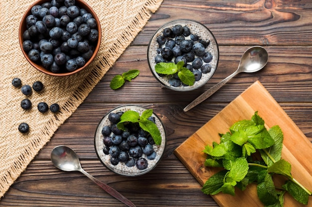 Café da manhã saudável ou manhã com sementes de chia pudim de baunilha e bagas de mirtilo no fundo da mesa dieta alimentar vegetariana e conceito de saúde Pudim de chia com leite de coco e mirtilo