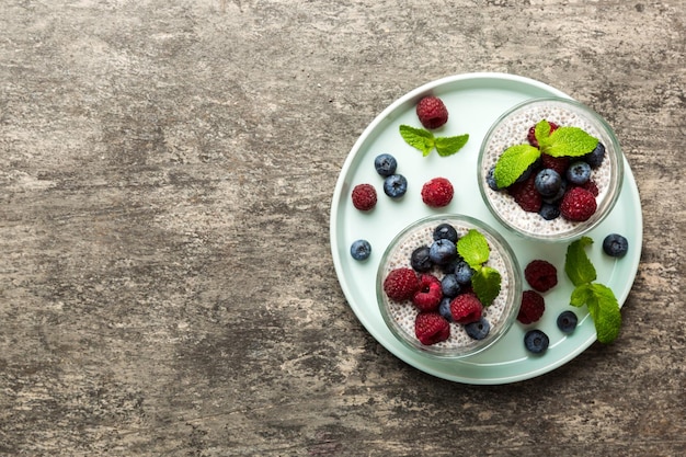 Café da manhã saudável ou manhã com sementes de chia pudim de baunilha framboesa e bagas de mirtilo no fundo da mesa dieta alimentar vegetariana e conceito de saúde Pudim de chia com framboesa e mirtilo