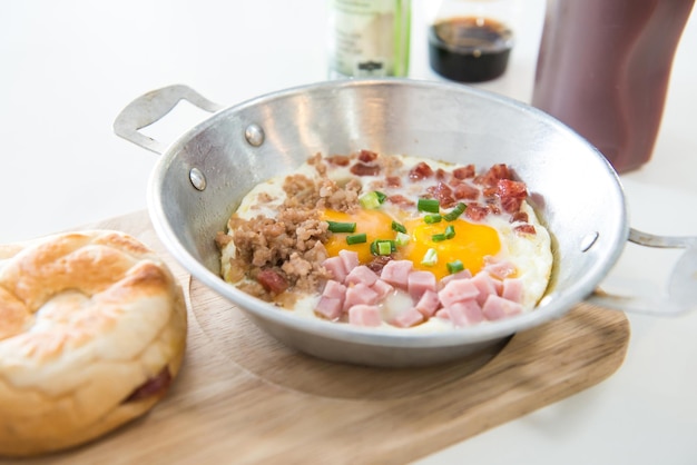 Café da manhã saudável ovos fritos presunto bacon porco na panela e pão na placa de madeira Foco seletivo