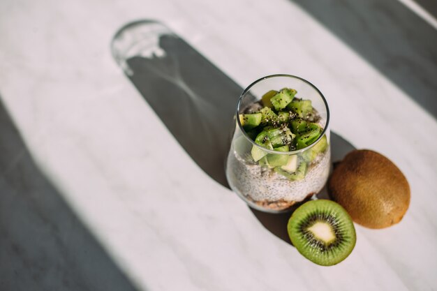 Café da manhã saudável. pudim de chia com kiwi e granola em vidro no fundo branco