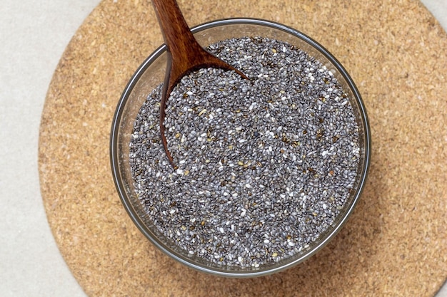 Café da manhã saudável Sementes de Chia ou superalimento em tigela de vidro com colher sobre fundo de textura de papelão