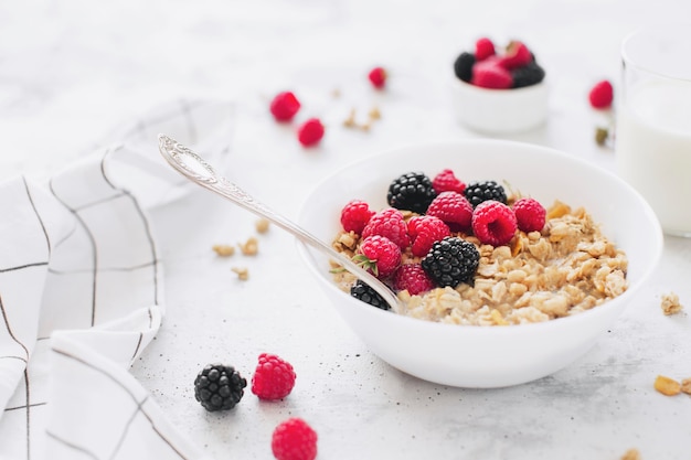 Café da manhã saudável, tigela branca cheia de granola, muesli, framboesa, amora preta na mesa de concreto cinza. Alimentação saudável, eco, conceito de bio comida. Refeição saborosa fresca em fundo cinza. Foto de qualidade