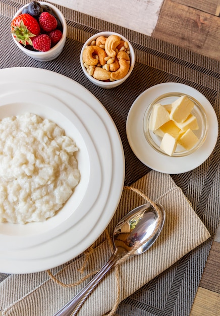 Café da manhã saudável. Tigela de mingau de arroz com frutas e nozes na mesa, comida de café da manhã quente e saudável, vista superior