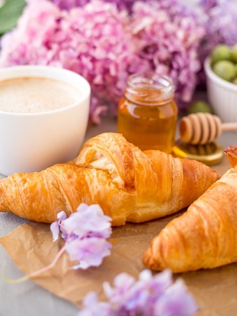 Café da manhã servido café e croissants perto de flores