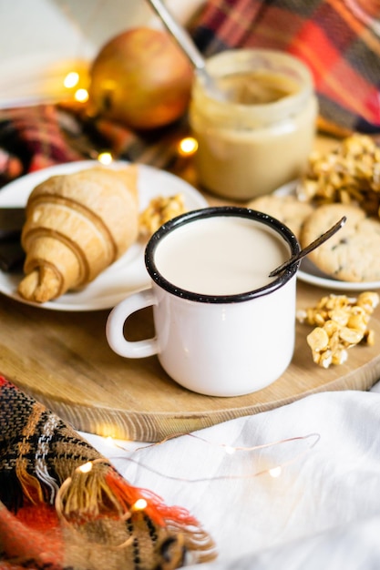 Café da manhã simples em casa de campo no café da cama com leite e pastelaria caseira no cobertor xadrez