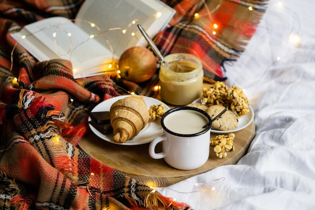 Café da manhã simples em casa de campo no café da cama com leite e pastelaria caseira no cobertor xadrez