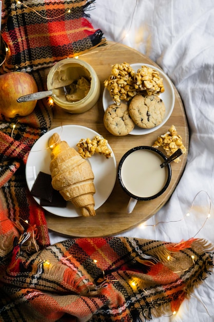 Café da manhã simples em casa de campo no café da cama com leite e pastelaria caseira no cobertor xadrez