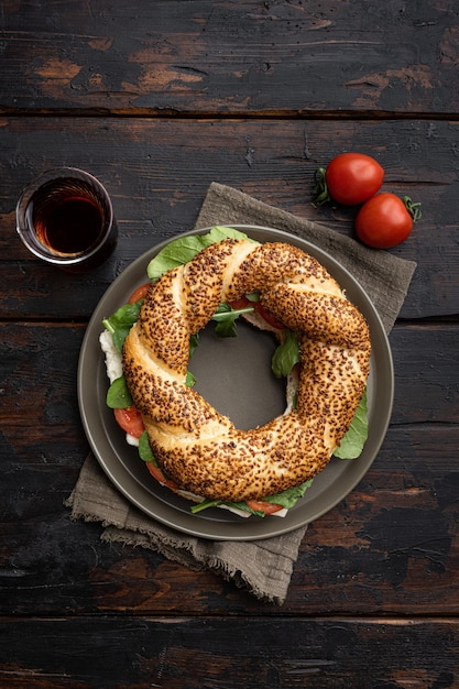 Café da manhã turco rápido Simit com queijo e verduras com copo de chá preto turco com copo de chá preto turco na velha mesa de madeira escura fundo vista superior plana com espaço de cópia para texto