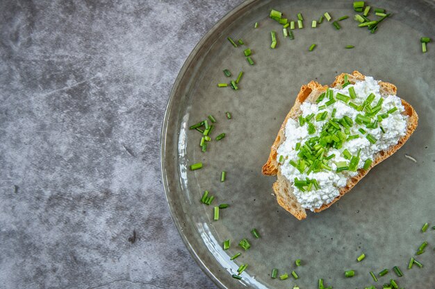 Café da manhã. um pedaço de pão manchado com queijo cottage com cebola verde