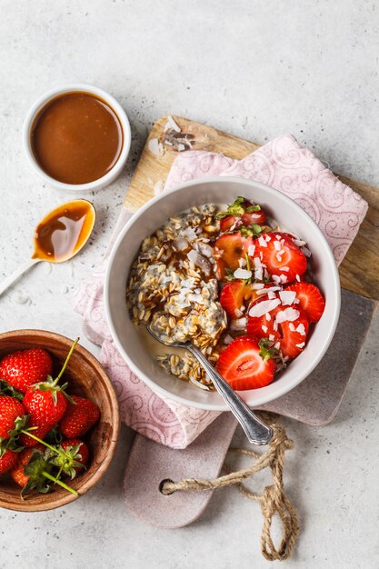 Café da manhã vegano. Aveia com sementes de chia, bagas, sementes e caramelo em tigela branca.