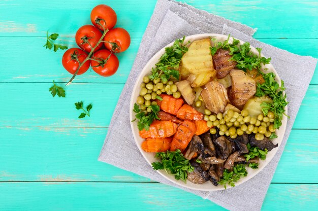 Café da manhã vegetariano: legumes cozidos (batatas, cenouras), cogumelos, ervilhas verdes em um prato