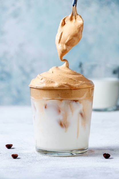 Café Dalgona gelado com colher. Café chicoteado cremoso na moda. Bebida fria de verão na Coréia do Sul