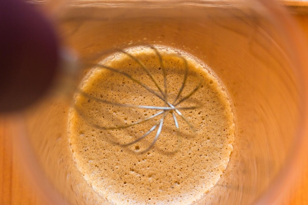 Café dalgona con leche en un vaso sobre mesa de madera