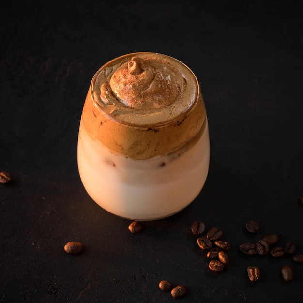 Café dalgona sobre fondo negro Bebida coreana con espuma de café