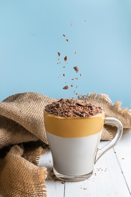 Café Dalgona sobre una mesa de madera blanca. chocolate en polvo vertido