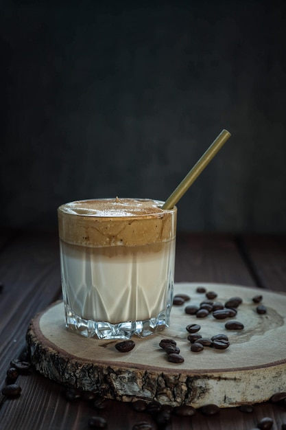 Café dalgona sobre una mesa de madera y granos de café tostados Bebida coreana con café