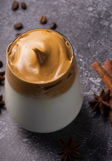 Café Dalgona en vaso junto a ramas de canela y anís