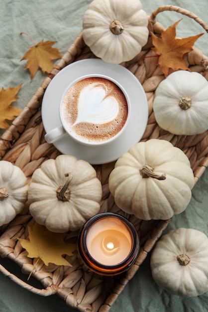 Café de abóboras brancas e folhas de outono em uma bandeja de vime