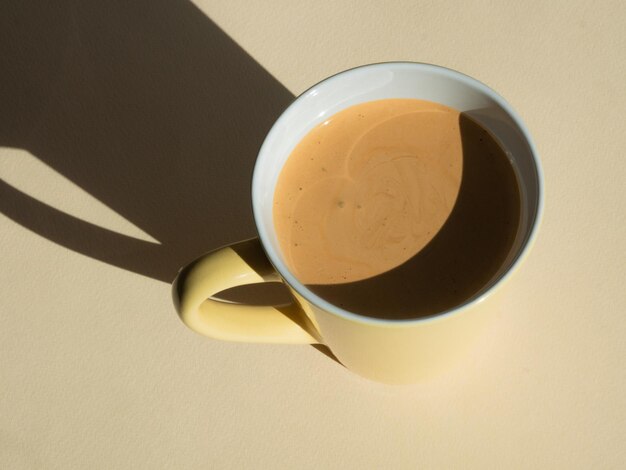 Café de caneca de cappuccino em bege com sombras duras em luz dura Minimalismo cores naturais Vista de cima