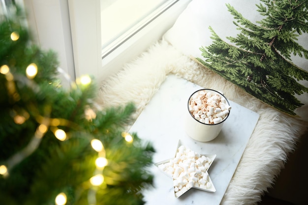 Café de inverno com marshmallow no aconchegante parapeito da janela com árvore de Natal