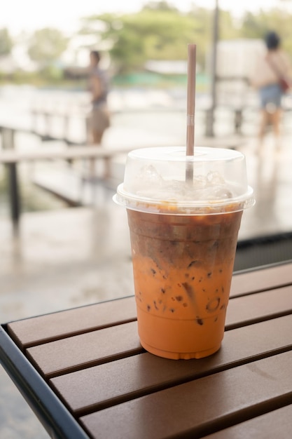 Café de leite misturado com chá de leite gelado mostrando separado em uma camada em vidro plástico em mesa de madeira no café