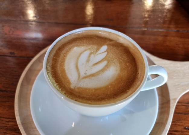 Café de loja lateral uma xícara de café com leite quente em fundo de madeira