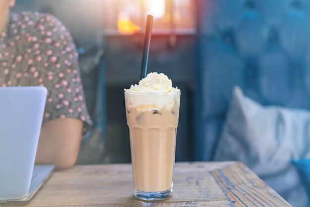 Café de mocha de gelo na mesa de madeira com o homem que trabalha usando o laptop