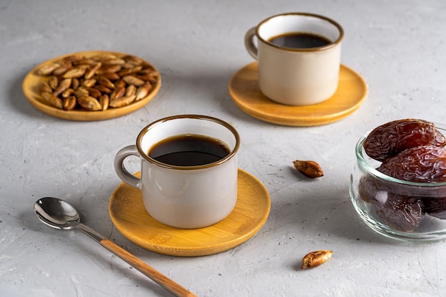 Café de semente de data saudável em duas xícaras data frutas e sementes em fundo de concreto cinza