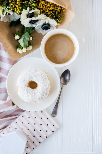 Foto café y donut con flores frescas