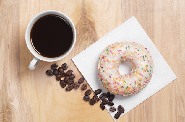 Café y donut glaseado sobre mesa de madera