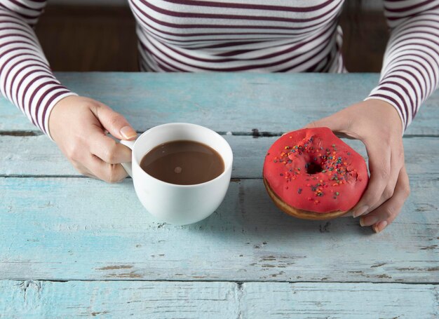 Café y donut de mano de mujer