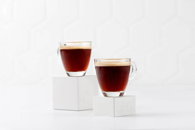 Café dos tazas con espresso en podios blancos y fondo de mosaico Aroma ristretto Vaso de café